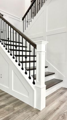 a white staircase with black railing and wood flooring