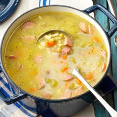 a large pot filled with soup on top of a blue and white table cloth next to a spoon