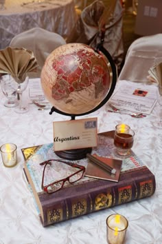 a table topped with books and glasses next to a globe