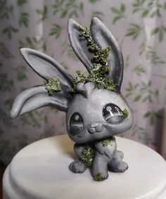 a small rabbit figurine sitting on top of a white cake covered in moss