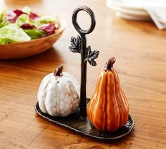 two small pumpkins sitting on a tray next to a bowl of salad and an iron hook