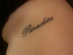 the word paradise written in cursive ink on a woman's lower back