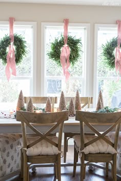 two christmas wreaths hanging from the ceiling above a dining room table with holiday decorations