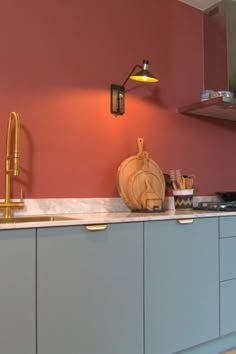 a kitchen with pink walls and blue cabinets is pictured in this image, there are wooden utensils on the counter