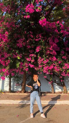 a woman standing in front of a tree with pink flowers