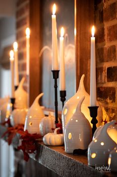 white candles are lined up on a mantle