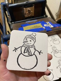 a hand holding up a drawing of a snowman