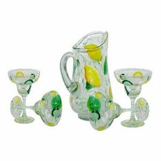 a glass pitcher and four glasses with lemons on them