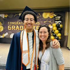 a man and woman pose for a photo in front of graduation decorations