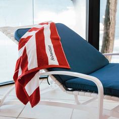 a red and white towel sitting on top of a chaise lounge chair next to a window