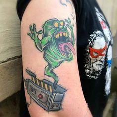 a man with a tattoo on his arm has an image of a cartoon character in front of him