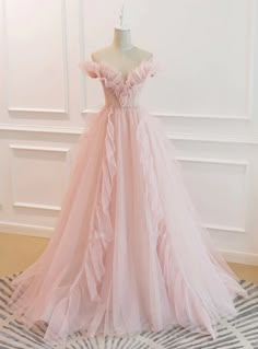 Enveloped in the tender hue of a blooming rose, this prom dress is a vision of delicate allure. The bodice, with its sculpted off-shoulder sleeves and artful ruching, is a masterpiece of texture and form. Subtle floral embellishments, meticulously placed, add a dimension of understated elegance. The full skirt, a cascade of soft tulle, lends an air of balletic grace, ensuring that each step is as enchanting as the last. This gown is for the prom-goer who wears her heart on her sleeve and desires a dress that speaks softly but resonates deeply. Tulle Long Prom Dress, Pink Evening Dress, A Line Evening Dress, Pink Wedding Dress, Tulle Evening Dress, Floor Length Prom Dresses, Pink Prom Dress, Pink Formal Dresses, Graduation Dresses