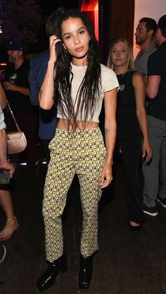 a woman with long hair standing in front of a group of people at a party