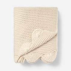 a white knitted blanket folded on top of each other with a knot at the end