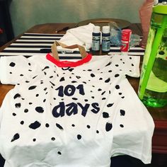 a white shirt with black spots on it sitting on top of a wooden table next to bottles