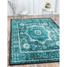 a blue area rug with an ornate design on the center and sides, in front of a white chair