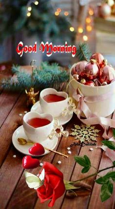 two cups of tea sitting on top of a wooden table next to christmas decorations and greenery