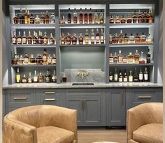 two brown chairs sitting in front of a bar filled with liquor bottles