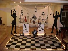 some people are standing in front of a table with musical notes on it and there is a checkerboard dance floor