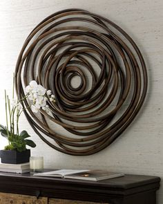 a wooden table with a vase on top of it and a metal circular wall decoration