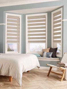 a bedroom with blue walls and white shutters on the windows, along with a bed