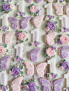 many decorated cookies on a table with flowers and butterflies in the shape of butterfly wings