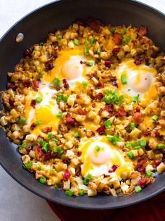 two eggs are fried in a skillet with chopped green onions and bacon on top