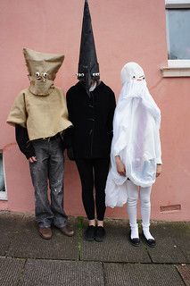 three people dressed up in costumes standing next to each other on a sidewalk near a pink building