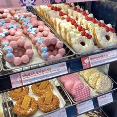 many different kinds of donuts on display in a store window with hello kitty stickers