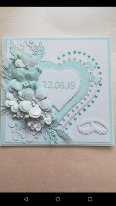 a wedding card with flowers and pearls in the shape of a heart on a table