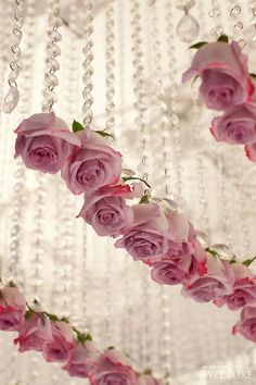 some pink roses hanging from a chandelier with beads on the bottom and sides