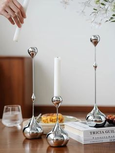 These sleek, silver candle holders add a touch of elegance to any table setting. The unique, teardrop shape and polished finish create a stunning centerpiece. Perfect for creating a cozy and inviting atmosphere. Decor Dinner Table, Steel Candle Holder, Silver Candle Holders, Silver Candle, Dinner Table Decor, Metal Candlesticks, Decoration Room, Metal Candle Holders, Table Decoration