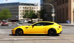 a yellow sports car driving down the street