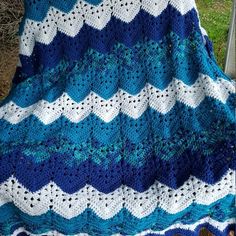 a blue and white crocheted blanket sitting on top of a chair