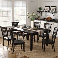 a dining room table with chairs and a rug on the floor in front of it