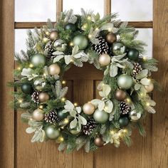 a christmas wreath hanging on a door with pine cones and evergreens in the center