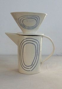 two coffee mugs stacked on top of each other, one with an oval design