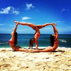 two women in bikinis doing yoga on the beach