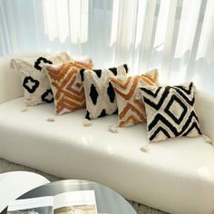 four pillows on a white couch in front of a window