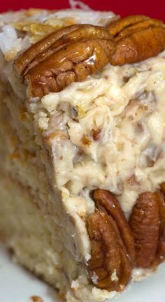 a close up of a piece of cake on a plate with pecans and icing