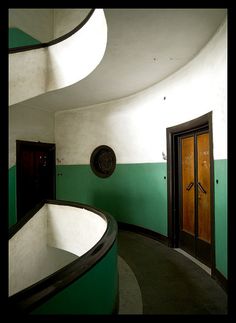 a room with green and white paint on the walls, an oval window in the center