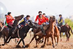 a group of men riding on the backs of horses in a dirt field next to each other