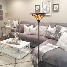 a living room with gray couches and white pillows on top of it's covers