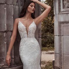 a woman in a wedding dress leaning against a stone wall