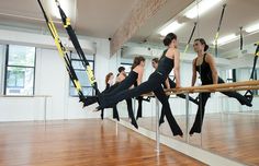 a group of women practicing aerial acrobatics in a dance studio with mirrors