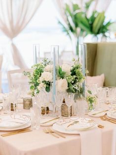 the table is set with white flowers and gold place settings for an elegant wedding reception