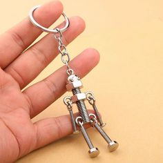 a hand holding a metal keychain shaped like a robot