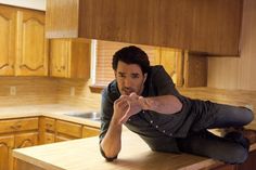 a man sitting on top of a counter in a kitchen