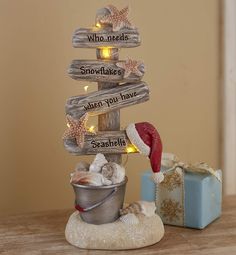 a christmas tree made out of driftwood with words written on it and seashells in a bucket