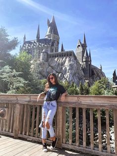 a woman standing on top of a wooden bridge next to a castle in the background